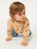 Child wearing a beige sweater with bear patterns on a white background