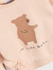 Beige outfit with a bear illustration and text on a plain background