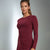 A woman modeling a matching burgundy long-sleeve knit top and high-waisted leggings set against a gray studio background.