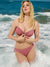 A woman modeling a dusty rose ribbed two-piece bikini with a front knot detail on the top, standing in ocean waves.
