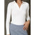 A woman wearing a fitted white long-sleeve polo-style top with a split V-neckline, paired with a blue textured skirt, shown against a dark gray wall.