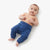A baby lying on their back wearing solid blue pants, photographed against a clean white background.