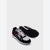 A pair of Puma sneakers in black, white, and pink, with one shoe standing upright to show the side profile and the other lying down to display the textured black outsole.