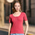 A woman wearing a short-sleeve scoop-neck henley top in a vibrant red, paired with light blue jeans, standing outdoors on a sunny street.
