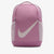 A pink Nike backpack with a large white Swoosh logo on the front, set against a plain light gray background.