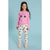 A young girl stands against a light blue studio background wearing a pink long-sleeve top with a rainbow and heart design, white leggings with a colorful heart pattern, and pink sneakers.