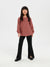 Young girl wearing a pink textured sweater and black pants on a white background