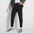 A person wearing slim-fit black jeans, styled with a gray button-up shirt, white t-shirt, and black-and-white sneakers against a light gray studio background.