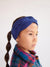 Child wearing a blue knitted headband with a plain background