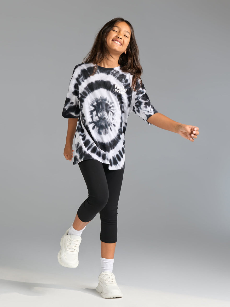 Person wearing a black and white tie-dye shirt and black leggings on a gray background