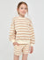 Young girl wearing a beige and white striped outfit on a light gray background