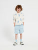 Child wearing a floral sweatshirt and light blue shorts on a white background