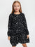 Young girl wearing a black dress with white star pattern on a white background