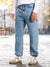 Person wearing light blue jeans and white sneakers on a blurred outdoor background