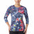 A woman wearing a long-sleeve athletic top with a colorful abstract paint-splatter pattern in blue, red, pink, yellow, and white, paired with black leggings against a plain white background.