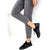 A person wearing slim-fit gray cuffed jeans and black low-top sneakers, shown from the waist down against a plain white background.
