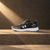 Black and gray running shoe with white sole on a white background
