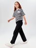 Girl wearing a black and white striped shirt and black pants on a white background