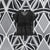A black short-sleeve lace top with a V-neck, displayed against a geometric black and white patterned wall.