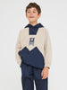 Child wearing a beige and navy color-blocked hoodie with a logo on a white background