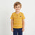 A young boy wearing a yellow and white striped short-sleeve henley shirt with a small navy logo on the chest, paired with navy pants, standing against a light gray background.