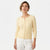 A woman wearing a pale yellow ribbed knit cardigan sweater with white pants, photographed against a clean white studio background.