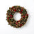 A festive Christmas wreath featuring a mix of brown faux leaves, green pine needles, and bright red berries, photographed against a clean white background.