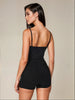 Woman wearing a black romper against a neutral background