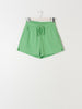 Green shorts on a hanger against a white background
