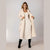 A woman models a long cream-colored textured coat over a matching ribbed knit dress, paired with black knee-high boots, against a neutral studio background.