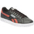 A Reebok low-top sneaker in black leather with coral red side stripes, a white rubber sole, and black laces, shown from a three-quarters angle on a white background.