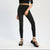 A model wearing black skinny jeans, a black cropped long-sleeve top, and black strappy platform sandals, standing against a light gray studio background.
