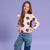 Young girl wearing a pink floral top and blue jeans on a purple background