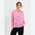 A woman modeling a pink and light pink watercolor-patterned long-sleeve button-up shirt with black pants, set against a plain light gray background.