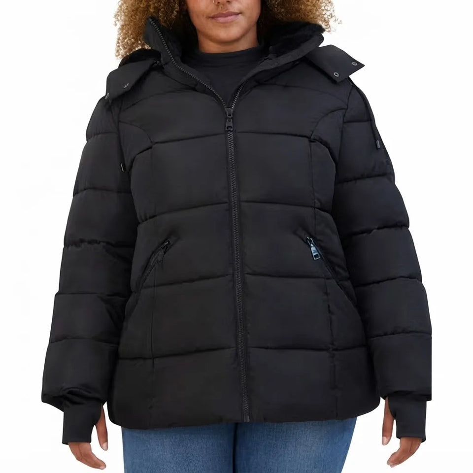 A woman wearing a black puffer jacket with a full front zipper, zippered hand pockets, and a high collar, paired with blue jeans against a plain white background.
