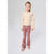 A young girl stands against a light gray studio background wearing a cream long-sleeve blouse with small black motifs and ruffled shoulders, paired with dusty rose corduroy pants and matching pink shoes.