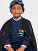 Child wearing a navy sweater with text, black coat, and checkered hat on a white background