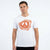 A man wearing a white crewneck t-shirt with a prominent orange graphic on the chest, set against a plain white studio background.