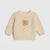 A cream-colored textured knit sweater for toddlers, featuring a small embroidered teddy bear face on the center chest, displayed against a light gray background.