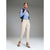 A woman models a stylish outfit consisting of a blue and white striped button-down shirt, a navy blue sleeveless vest, beige slim-fit trousers, and black strappy high-heeled sandals, set against a neutral gray studio background.