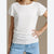A woman wearing a white short-sleeve lace top and light blue jeans, cropped from the shoulders to the hips against a plain beige studio background.