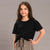 A young girl modeling a black short-sleeve t-shirt and leopard print shorts against a solid gray studio background.