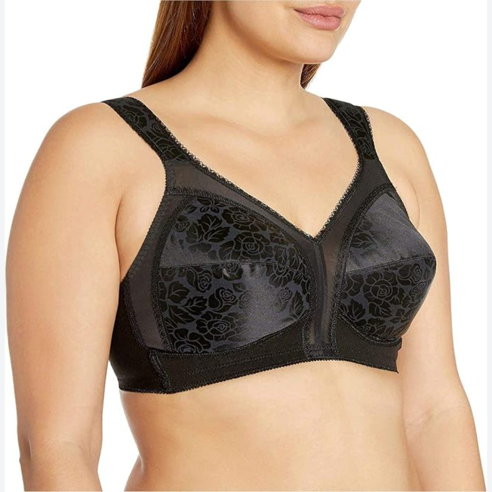 A close-up of a woman wearing a black sheer floral lace bra with mesh panels and wide shoulder straps, shown against a plain white background.