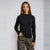 A woman modeling a black long-sleeve mock neck top paired with leopard print pants, standing against a light gray studio background.