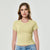 A woman modeling a pale yellow short-sleeve crewneck crop top paired with light blue jeans, set against a plain light gray studio background.