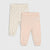 Two pairs of toddler leggings laid flat on a light gray background. The pair on the left is cream with a small pink cherry print, and the pair on the right is solid pale pink.