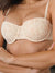 A close-up of a woman wearing a light beige underwire bra with a subtle pink floral pattern, showing the cups and thin straps against her torso.