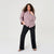 A woman modeling a red and white vertically striped button-down shirt with black wide-leg pants, standing against a plain light gray studio background.