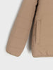 Close-up of a beige quilted jacket on a light gray background