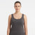 A woman wearing a dark gray scoop-neck tank top, photographed against a clean white studio background.